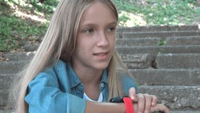 Child Talking at Smartwatch in Park, Girl Playing Browsing Internet on Smart Watch, Kid Using a Smartphone, Children use Device