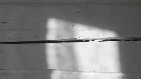 White uneven wooden log wall of rough texture with a sunspot from the window. Country style. Abstract background. Shadow and light. Natural old plank. Gray color. Daylight. Interior. 4K video footage.