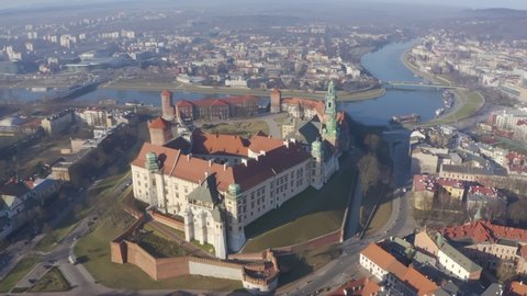 Aerial drone video to Wawel castle on the hill and wisla river. Beautiful morning sunrise. City panaramic drone view from above. Poland Krakow famous tourist historical attractions. Sunny spring 