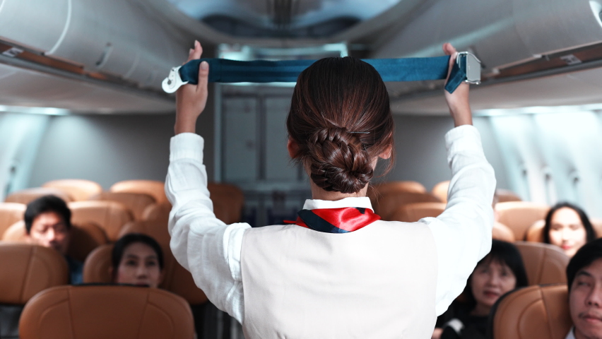 Asian beautiful female flight attendants explaining passengers how to use seat belt fastening in emergency situation flight attendants in uniform safety demonstration concept airplane.Aircraft safety. Royalty-Free Stock Footage #1090633203