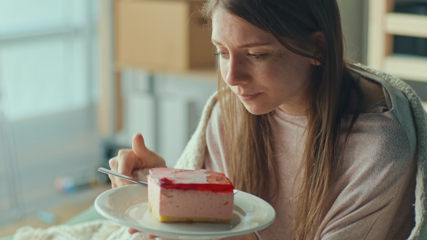 Heartbroken Girl Sitting on Sofa Crying, Eating Cake. Upset Young Woman Wrapped in Blanket Worry Separation or Divorce. Atmosphere of Depression. Difficult Period of Life Having Psychological Problems | Shutterstock HD Video #1090634515