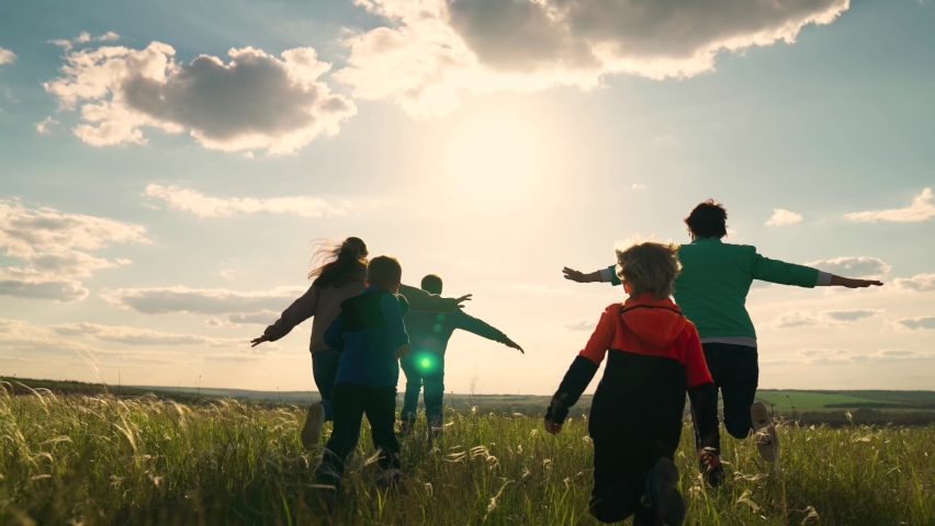 Happy family team, children, parents, run together in sun in park on grass. Concept Family game father mother daughter son fun running. Childrens dream, mom dad little children, holiday in nature