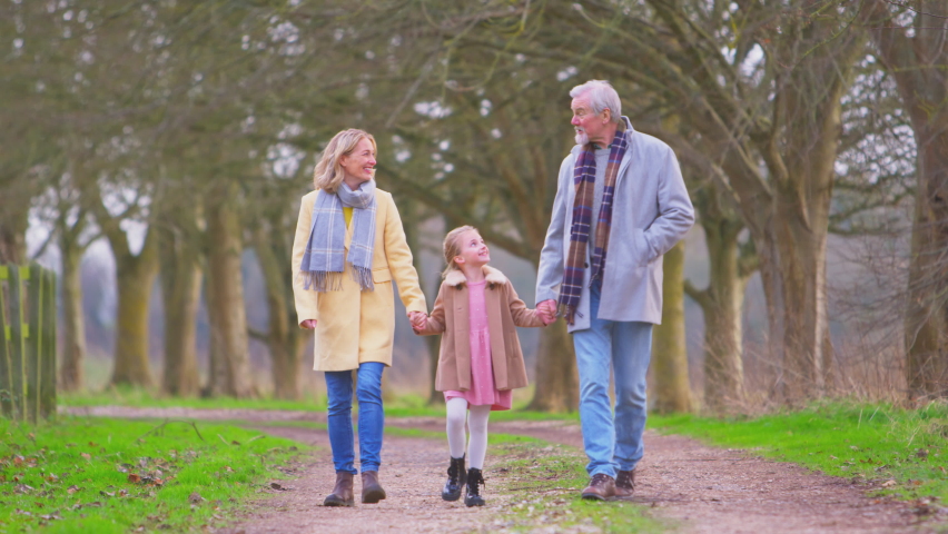 Grandparents swinging granddaughter as they walk along autumn or winter track in countryside - shot in slow motion Royalty-Free Stock Footage #1090641565