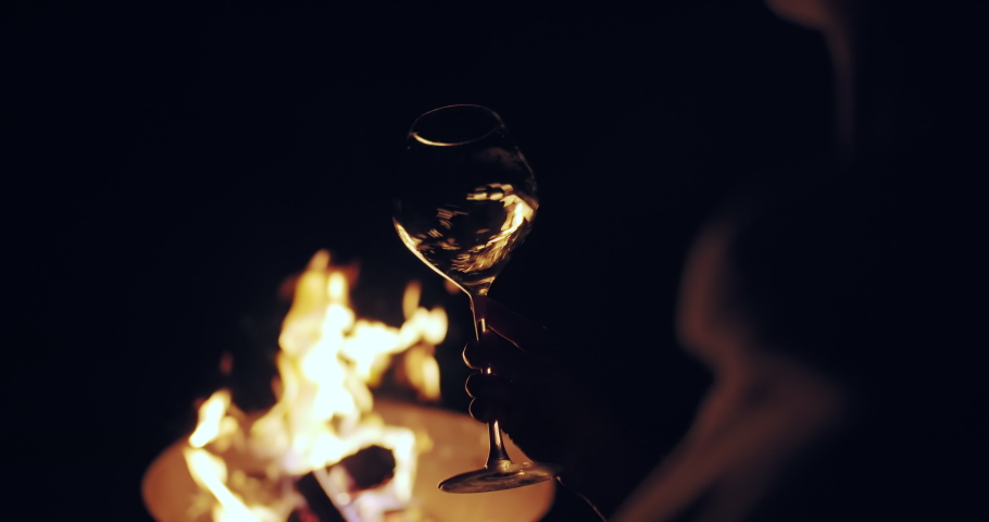 Tasting white wine at night. Glass of white wine slightly shaking against camp fire background. Winemaking in France, Provance.  Royalty-Free Stock Footage #1090646563