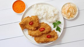 Crispy chicken fried in breadcrumbs served with rice. View from the top on white wooden background