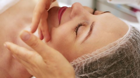 Beautician cosmetologist makes lymphatic drainage facial massage, professional cosmetic procedure in a beauty clinic salon for client. Skin care and cosmetology spa concept.