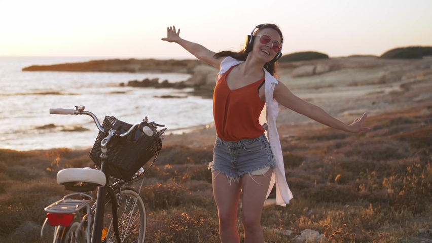 Portrait of happy excited carefree woman in headphones dancing in slow motion on Mediterranean sea beach smiling. Joyful Caucasian tourist listening to music enjoying hobby on vacations on Cyprus Royalty-Free Stock Footage #1090648103