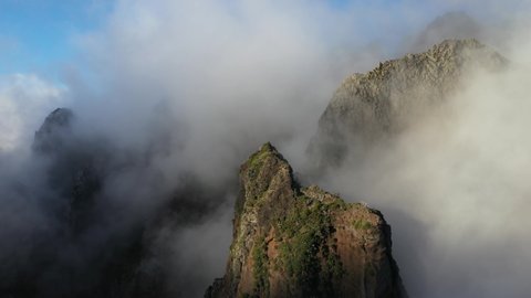 Drone shot moving backwards in the sunny and foggy landscape above Pico das Torres in Madeira.
