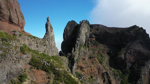 Drone shot flying up towards the peak where a group of 3 friends are standing together on top of Pico das Torres in Madeira.