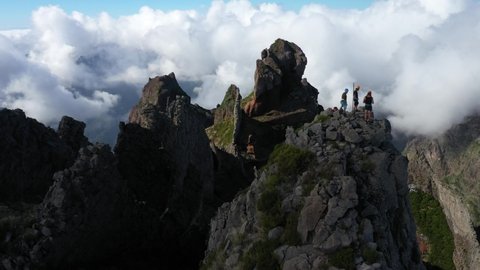 Circling drone shot around a group of 3 friends at the top of Pico das Torres in Madeira.