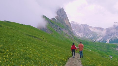 couple on vacation hiking in the Italien Dolomites, Amazing view on Seceda peak. Trentino Alto Adige, Dolomites Alps, South Tyrol, Italy, Europe. Odle mountain range, Val Gardena. Majestic Furchetta