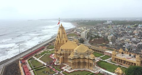 somnath , Gujarat , India - 05 23 2022: Aerial drone rotating shot of Somnath mandir with cityscape and sea in the background. Lord Shiva temple in Gujarat, India. Arabian sea and Somnath city view.