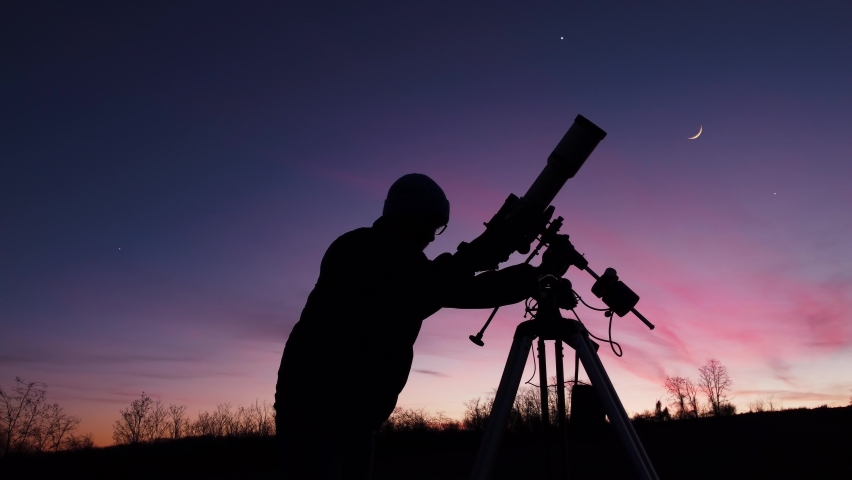 Silhouette of a man, telescope, stars, planets and shooting star under the night sky.