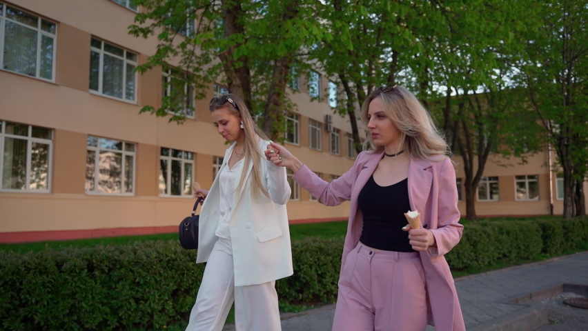 Adult girlfriends walking at street talk and laugh. Young women touch each other. Happy girls people spending time together