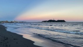 FUJISAWA, KANAGAWA, JAPAN - JULY 2021 : View of sunset beach and magic hour sky at Shonan area near Enoshima island. Wide view, real time shot in dusk. Japanese romantic summer season concept video.