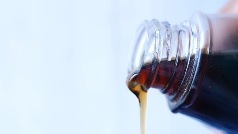 Bottle of maple syrup pouring close up 