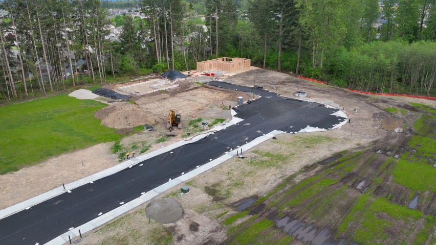 Aerial pulling away from a house under construction to reveal the many houses that will be built on the remaining land.