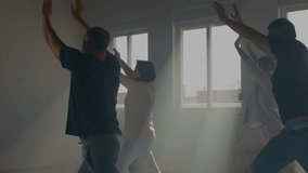 Peaceful senior people practicing tai chi indoor. Medium shot of men and woman exercising with trainer in gym, bending toward legs, performing slow movements. Chinese martial arts, sport concept - Powered by Shutterstock - Get 15% off with code: PIKWIZARD15