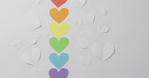 Video of colorful paper hearts lying on white background. gay pride, lgbt rights and supporting minority concept.