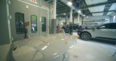 Staten Island, New York United States - May 20,  2022: Automotive Body Shop, repair technicians reassemble vehicle damaged in auto collision. Wide view of repair shop.