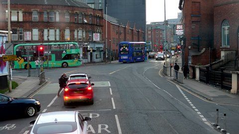 SALFORD, ENGLAND, UNITED KINGDOM - 03.24.2022: Colourful double-decker buses turning to Chapel Street in Salford city, upper deck windscreen view.