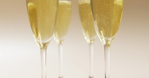Video of champagne in glasses on beige background. alcohol, beverage, drinks, party and celebration concept.