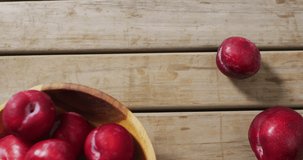 Video of fresh plums in bowl lying on wooden surface. food, fruits, freshens, taste and flavour concept.