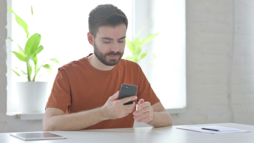 Young Man Talking on Phone, Discussing Work