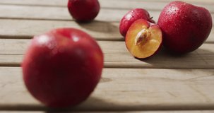 Video of fresh plums lying on wooden surface. food, fruits, freshens, taste and flavour concept.