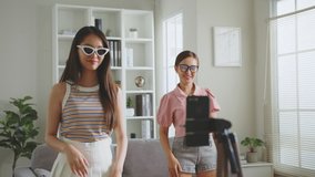 Asian young woman with her friend created her dancing video by smartphone camera together. To share video on social media application 