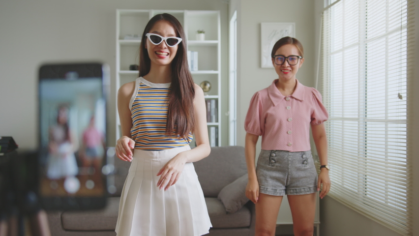 Asian young woman with her friend created her dancing video by smartphone camera together. To share video on social media application  | Shutterstock HD Video #1090688743