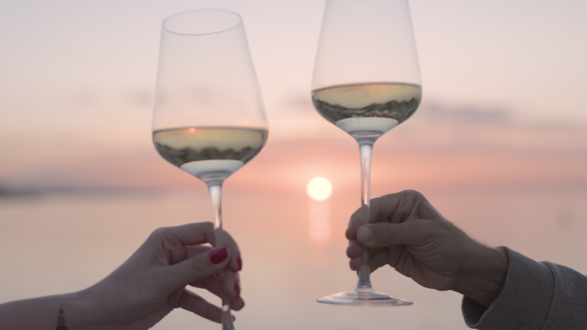 Two hands making a cheers with wine glass against sparkling sea and sky at sunset | Shutterstock HD Video #1090689711