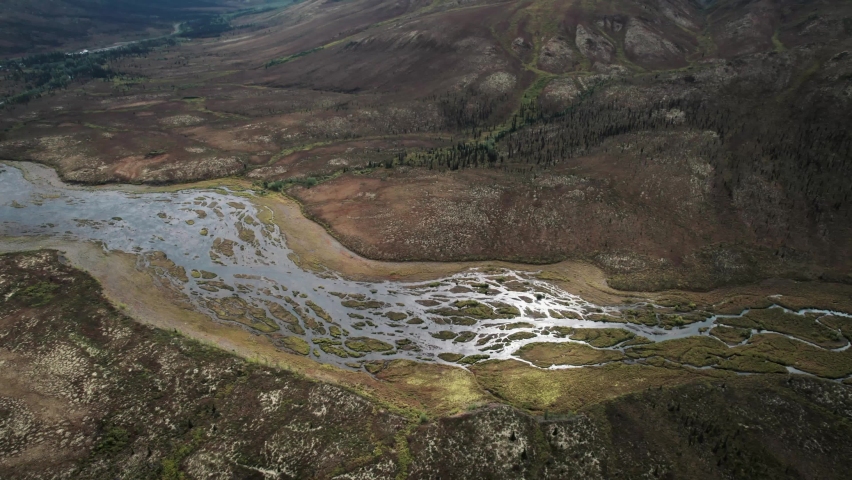 A river in mountain valleys with permafrost landforms, aerial reveal shot