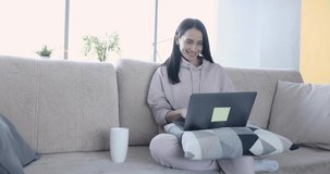 Young happy woman working on laptop remotely from home
