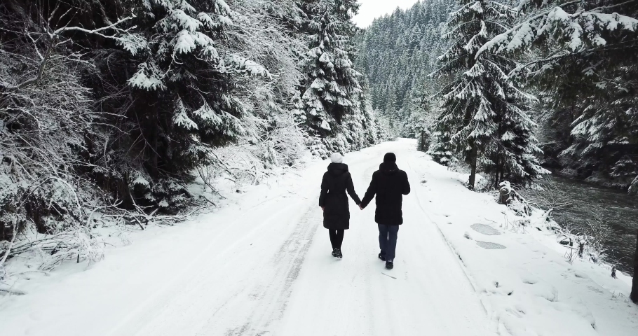 Aerial overpass steam goes on the road in the woods during a snowy winter. Happy couple 