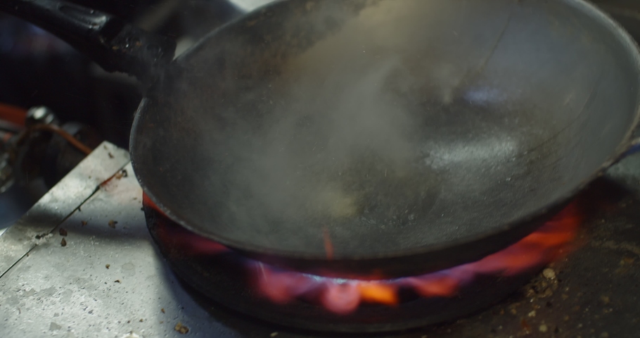 Close up Stir-Fried Chinese Morning Glory or Water Spinach in frying pan with fire flame at the kitchen, Asian Thai food, popular street food menu in Thailand