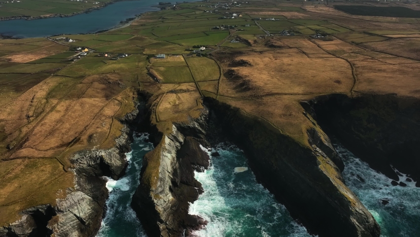 Portmagee Cliffs, Kerry, Ireland, March 2022. Drone slowly tracks south along the rugged coastline on the Iveragh Peninsula with Portmagee town and Valentia Island in the distance.