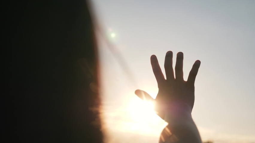 Close-up of a man girl hand at sunrise. hand reaches for the sun against the background of the sky. Sunrise hand silhouette reaching dream. hand girl of a man in the sunbeams of the sky. Royalty-Free Stock Footage #1090710539
