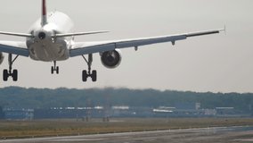 Slow motion shot of landing jet liner, rear view from end of runway. Passenger plane fly down and touch ground - Powered by Shutterstock - Get 15% off with code: PIKWIZARD15