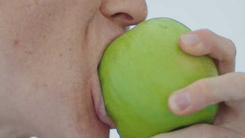 Woman bites and chews green apple