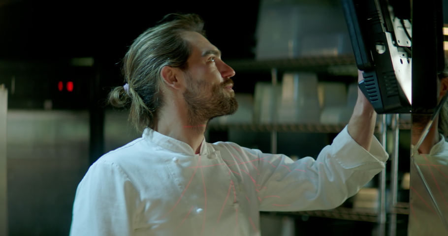 TRACKING Chef working on commercial restaurant kitchen, checking new orders on a display. Shot with 2x anamorphic lens