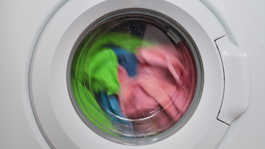 washing colored clothes in washing machine. automatic washer in operation, rotation multicolored things through glass door. laundry washing Royalty-Free Stock Footage #1090723503