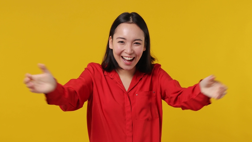Excited jubilant overjoyed happy young woman of Asian ethnicity 20s years old wears red shirt doing winner gesture celebrate clenching fists say yes isolated on plain yellow background studio portrait