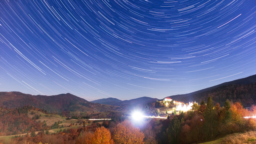 Timelapse of moving star trails in night sky. The Milky Way galaxy rotating over the mountain range in summer time