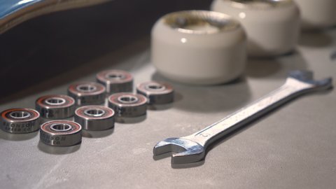 LA, UNITED STATES, APRIL 2022: CLOSE UP: Detailed overview of brand new set of skateboard wheels and bearings. Ordered sequence of individual skateboard parts and tool on countertop ready for assembly