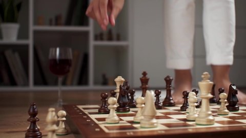 The girl makes a move with a chess piece queen. Strategy chess battle party. A woman's hand performs the move of a chess piece, the concept of a strategy for spending leisure time at home with benefit