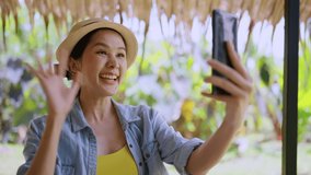 say hi gesture greeting video calling to family abroad connection,asian female digital nomad using smartphone calling to say hi her family or friend while vacation travel at the beach working anywhere