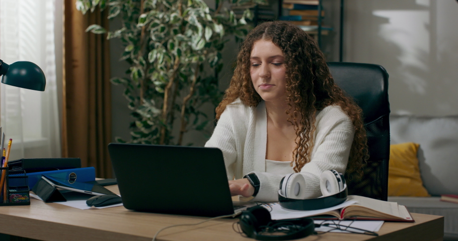 Woman sits at desk in front of laptop, sends messages, laughs, smiles, chats with boyfriend, girl in love is dreamy thoughtful happy to be invited to date victory.