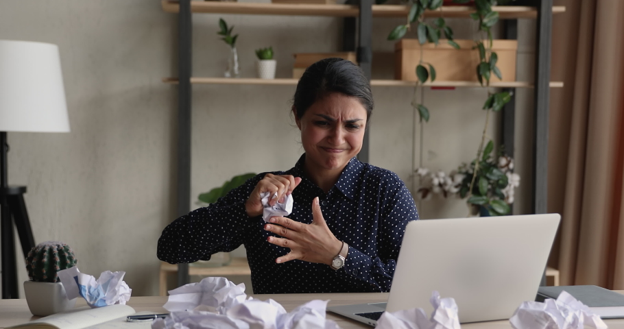 Angry confused young Indian office employee clerical worker sort out documents feels enraged lost patience throwing crumpled papers having nervous breakdown at work, deadline business problems concept | Shutterstock HD Video #1090734465