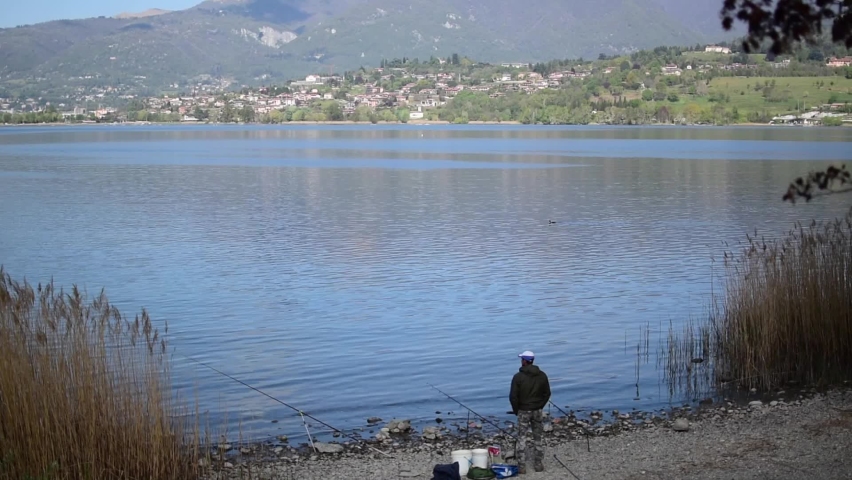 panoramic shot of a fisherman shoulders that is fishing in relax state with three fishing rods